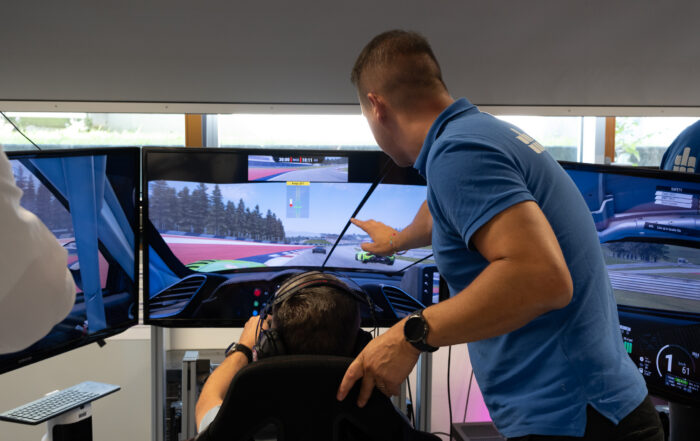 Prof. Dr. Matthias Vodel (rechts im Bild) unterstützt einen Teilnehmer beim Rennen im Simulator des Living Labs. (Bildquelle: Josefine Welk)